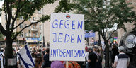 Ein Mann hält auf einer Kundgebung in Berlin-Neukölln im Jahr 2021 ein Schild mit der Aufschrift "Gegen jeden Antisemitismus" hoch. Darüber ist ein kleines Antifa-Logo zu sehen.