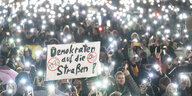 Mehrere Menschen nehmen am 23. Januar 2024 in Darmstadt an einer Demonstration gegen Rechtsextremismus und die AfD teil. Dabei steht auf einem Plakat «Demokraten auf die Straßen». Zum Abschluss der Kundgebung halten die Teilnehmer im strömenden Regen ihre